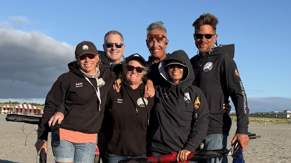 Team KiteLife members smiling together on the beach in Long Beach, Washington, holding packed-up kites